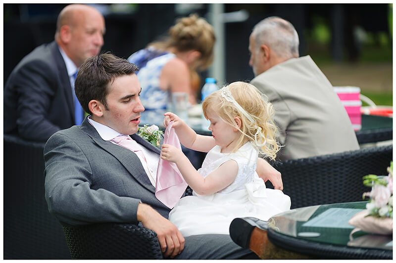 flower girl sat in gents lap playing with handkechief