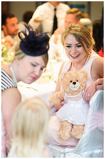 bridesmaid holds teady bear for flower girl