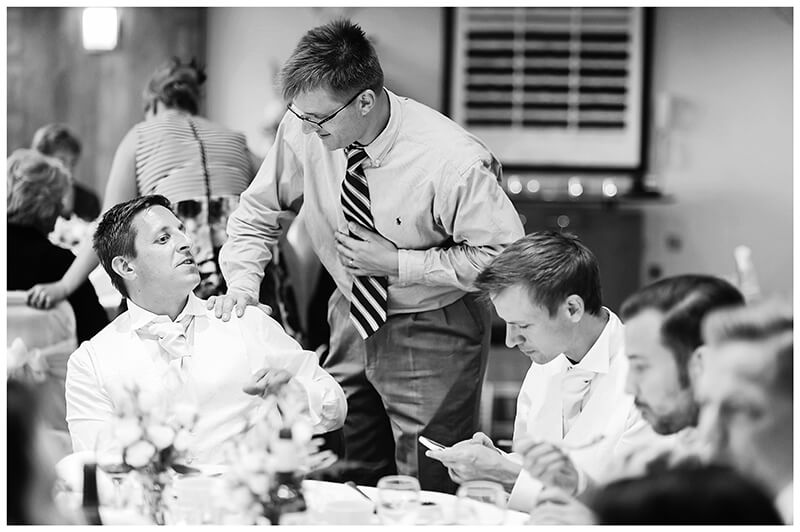 male wedding guests talking at dining table