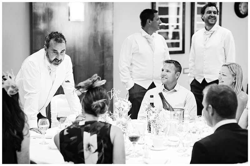 groom talking to guests sitting at dining table