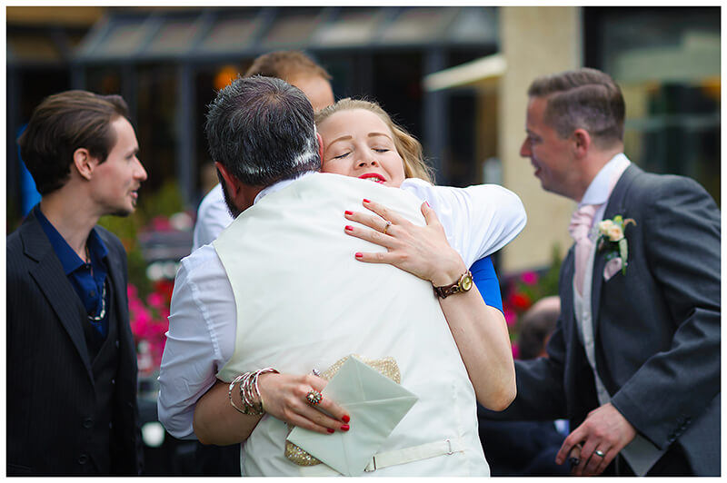 female wedding guest hugs groom