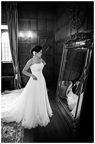 hengrave hall wedding bride in front of mirror bridesmaid reflected in mirror adjusting bottom of dress