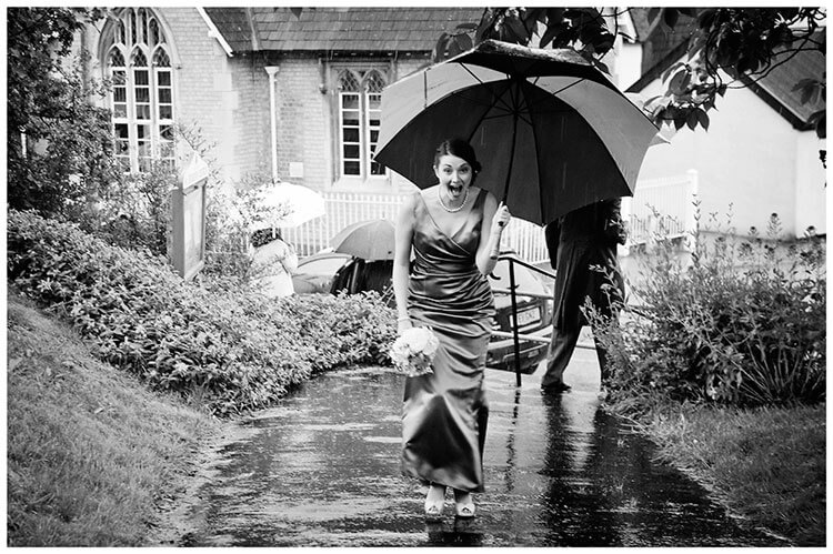 laughing bridesmaid under umbrella covering from rain