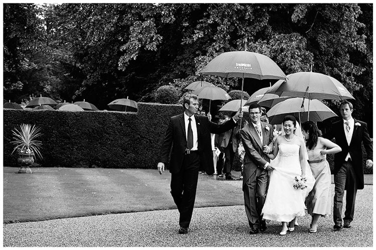 wedding party walking under umbrellas