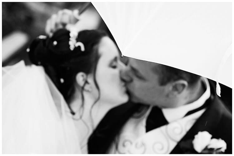 bride groom kissing under umbrella