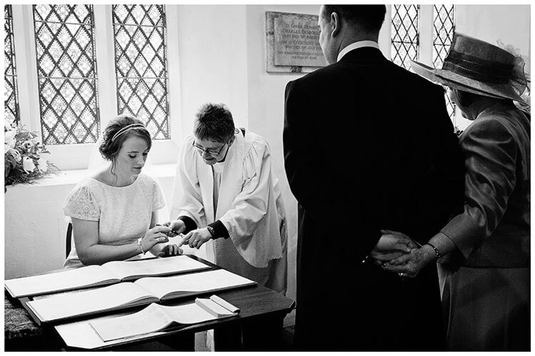 bride signs register as groom holds hands with his mother