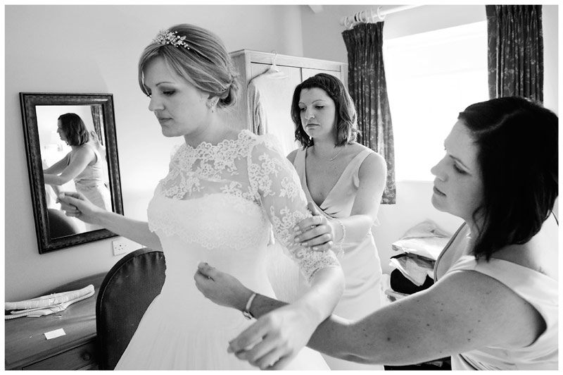 bride maids assist bride into dress