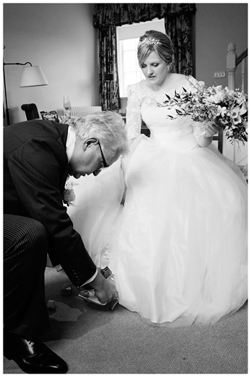 father helps the bride with her shoes