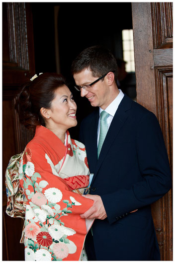 Japanese bride and her groom in door way embrace