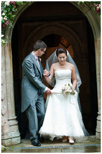 exiting hengrave Hall church groom holding brides dress