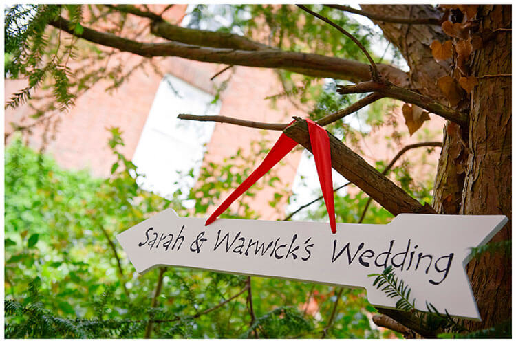 Leicestershire Kirby Muxloe wedding arrow sign with red ribbon hanging in tree