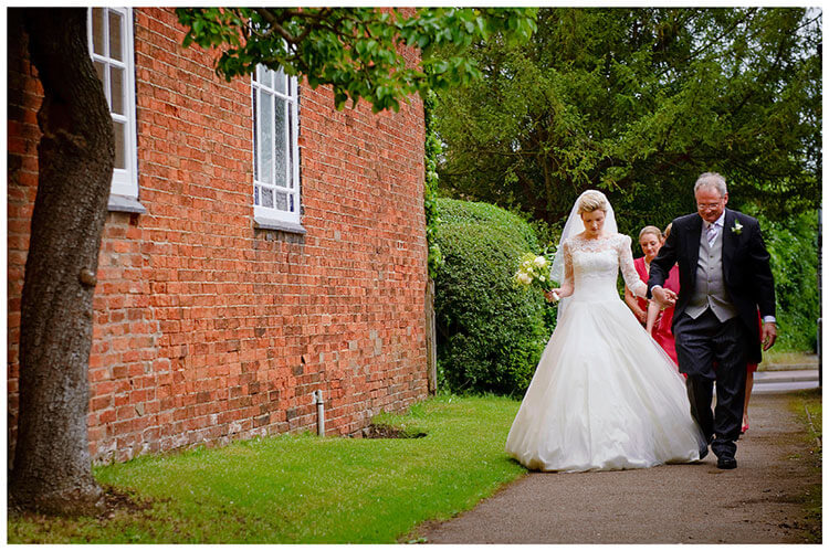 Leicestershire Kirby Muxloe wedding bride walking towards church holding hands with father
