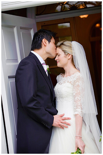 Leicestershire Kirby Muxloe wedding groom kisses brides forehead while standing in doorway