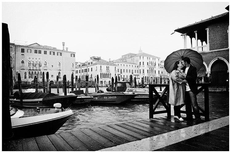 Venice Post Wedding Shoot photography couple kiss next to Grand canal under umbrella in rain