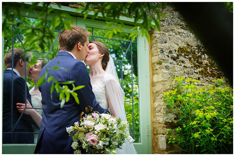 Choosing your perfect wedding photographer bride groom kiss next to mirrored doors showing reflection in garden