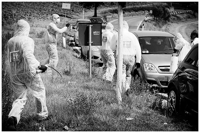 wedding Guests in coveralls surround cars in Tuscany countryside