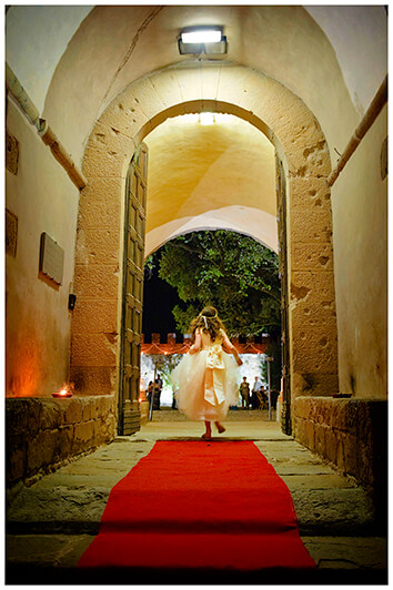 flower girl running along red carpet in to grand door way of Castel di Poggio Tuscany 