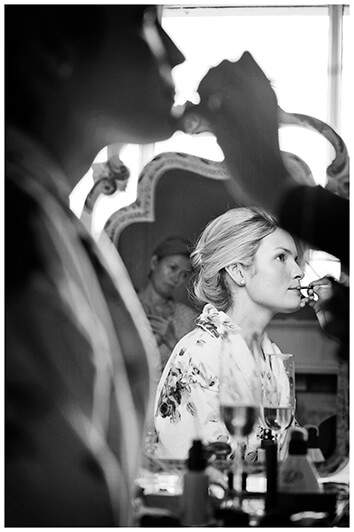 bride having lipstick applied bridesmaid watches reflected in mirror
