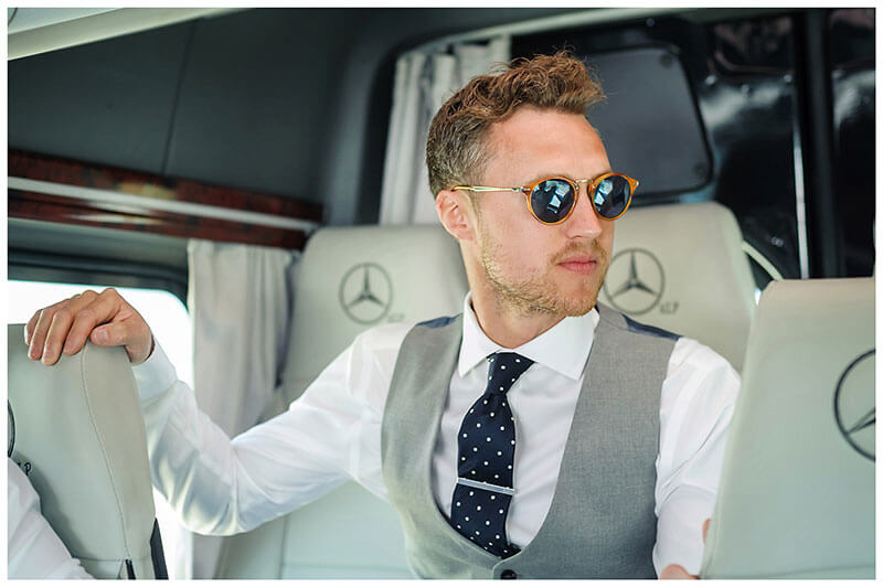 groom wearing sunglasses sat in transport on way to Royal Myconian Resort