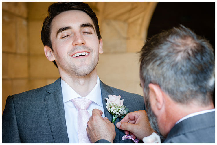 Groom lets out a nervous sigh as his button hole is fixed