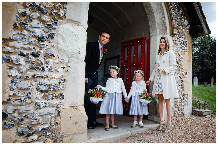 flower girls with their mother and father waiting in enterance of church for bride to arrive