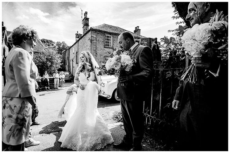 Smiling bride met by parents at St Peters church, Edensor gate