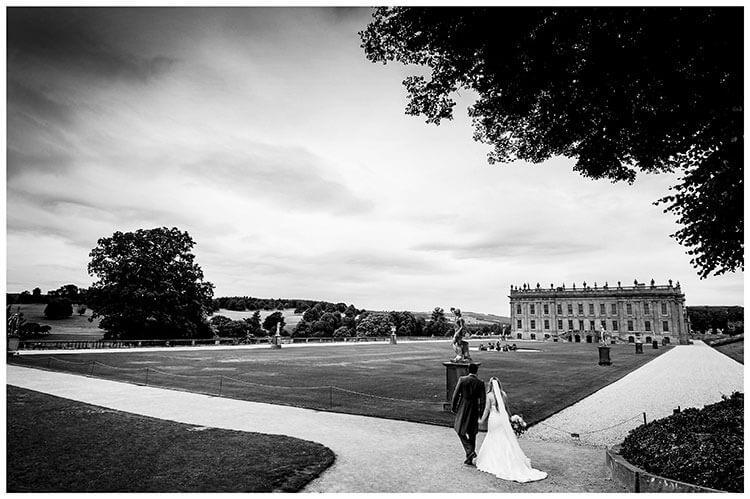 Couple hold hands as they walk towards Chatsworth House during their favourite wedding photography 2018