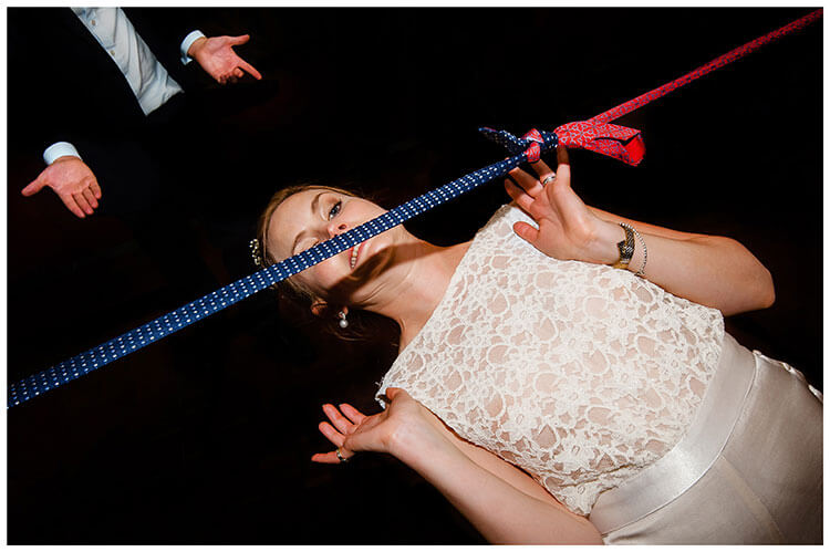 Bride limbo dancing under blue and red ties at Smallfield Place favourite wedding photography 2018