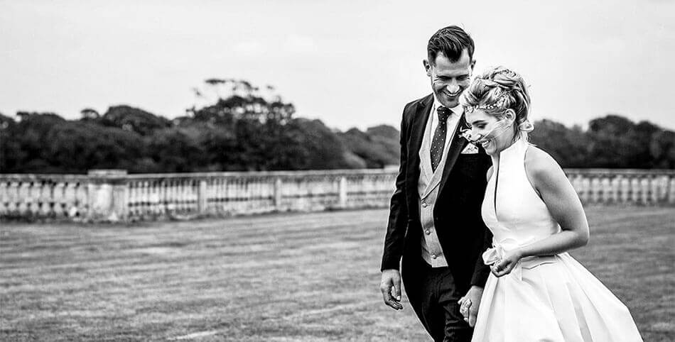 Smiling groom turns to his bride while they walk through the grounds of Pylewell park in hampshire